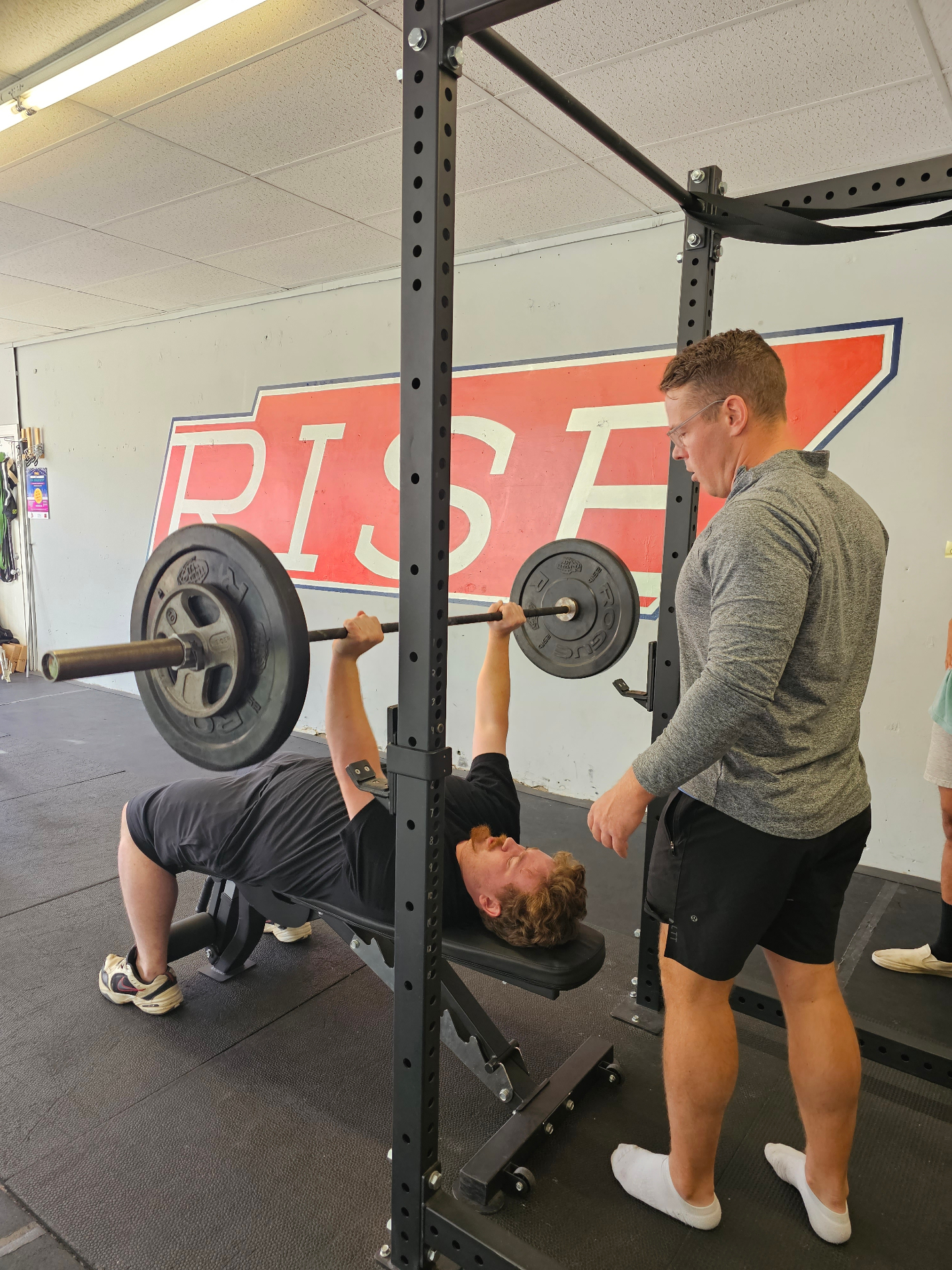 Rise member bench pressing with a coach spotting in Lebanon